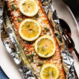 A large salmon fillet topped with lemon slices and fresh dill, baked in foil for easy cleanup. Great for an easy romantic dinner date.