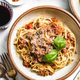 A satisfying bowl of Spaghetti Bolognese topped with fresh basil and parmesan, one of the best recipes to cook for a date.