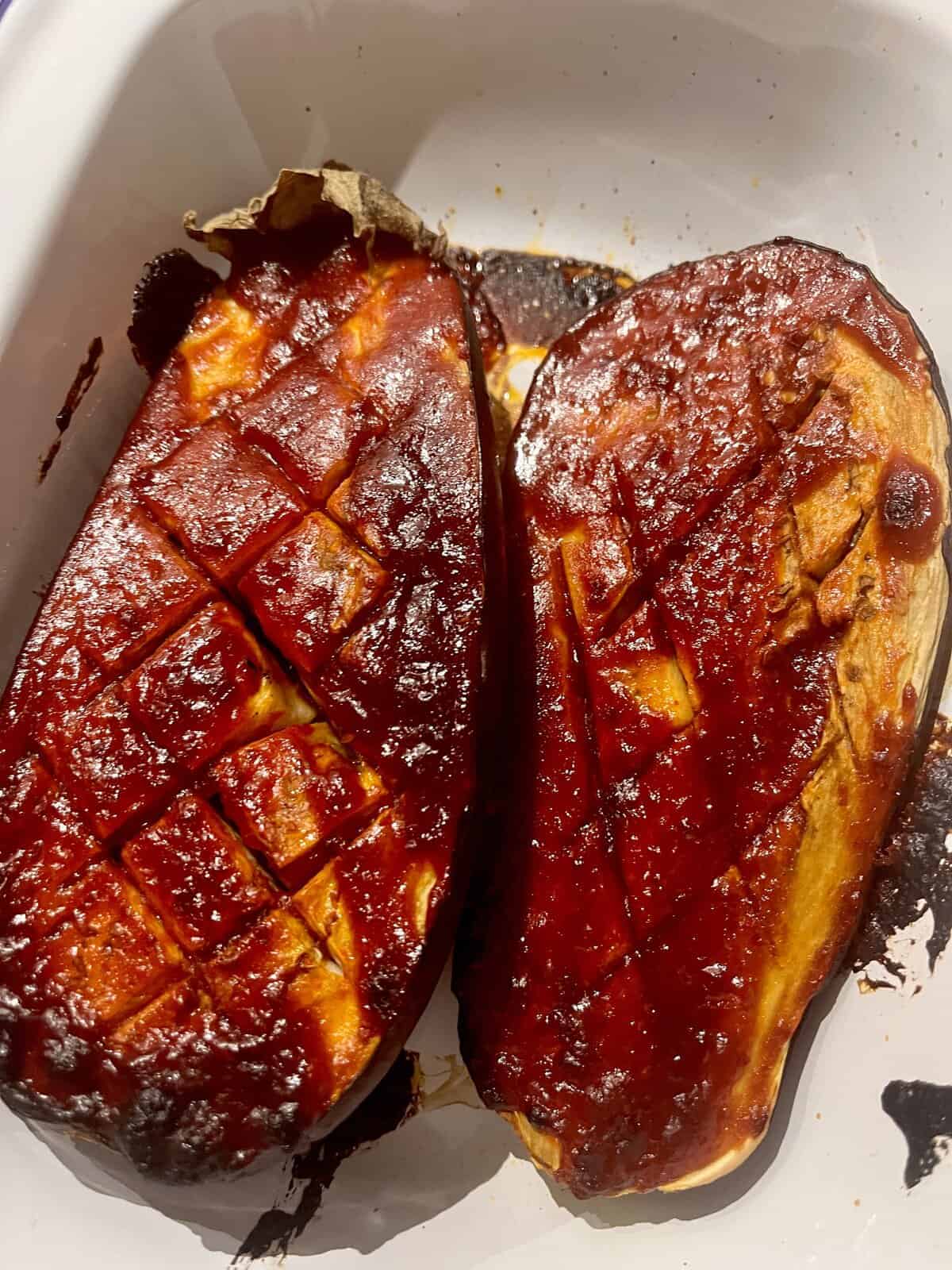 2 Baked Gochujang Aubergine halves in a roasting pan.