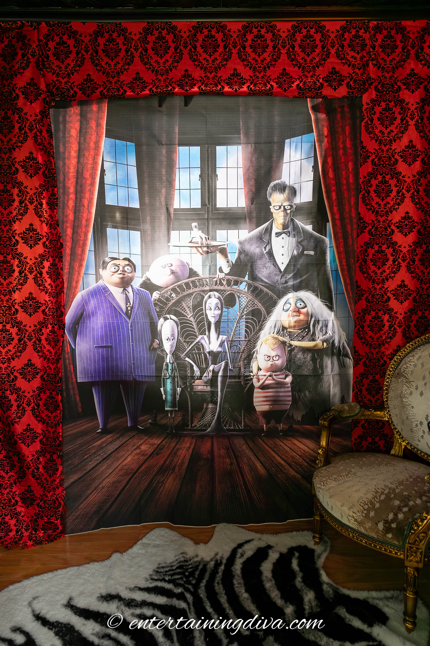 A large lighted wall picture of the Addams Family with a red curtain around it