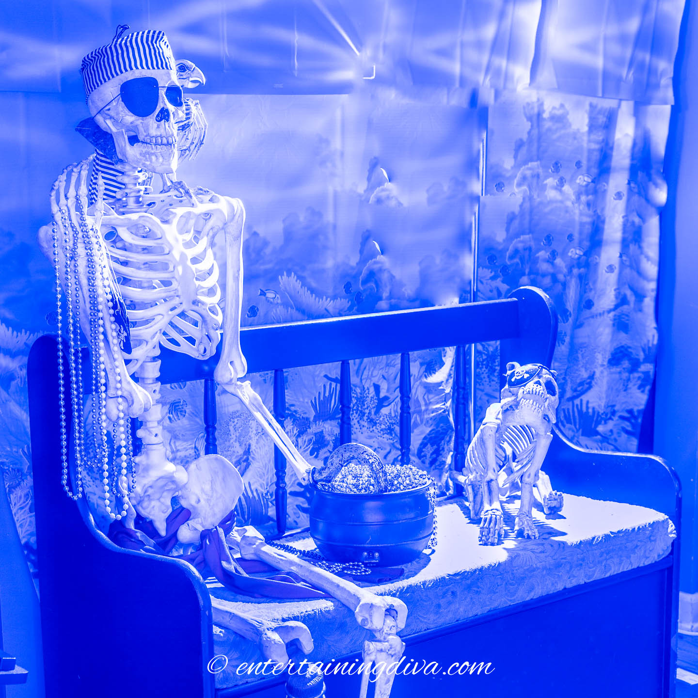 A pirate skeleton and dog sitting on a bench beside a pot of gold at an under the sea party