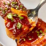 Scooping a spoonful from half a roasted butternut squash in gochujang sauce.